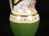 a green and white vase with a gold handle on a black background