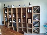 bottles of wine sit on shelves in a room with a table and chairs