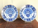 deux assiettes bleues et blanches posées sur une table en bois, avec un mur en arrière-plan