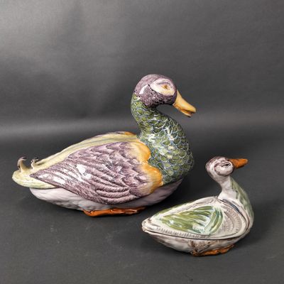 deux canards en céramique assis l'un à côté de l'autre sur une surface noire