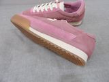 pink sued sneakers with white laces on a grey surface