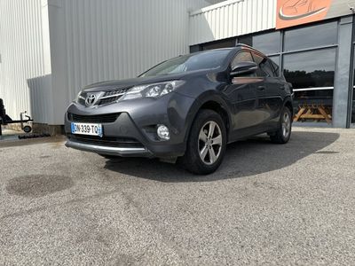 La Toyota RAV est garée devant un immeuble, sur un parking.
