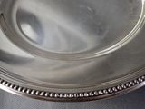 a silver plate with a beaded edge sitting on a table