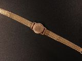 a close up of a gold watch on a black surface