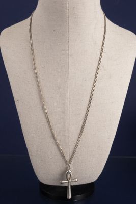 un mannequin blanc portant une croix en argent autour du cou