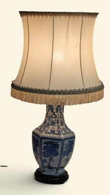 une lampe de table bleue et blanche, surmontée d'un abat-jour blanc