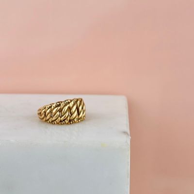 an image of a gold ring sitting on top of a marble block