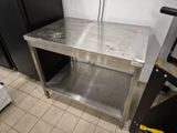 a stainless steel table in a kitchen with a black refrigerator
