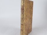 an old book sitting on top of a white table next to a white wall