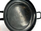 a black pan with a handle on a white surface