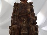 une vieille statue en bois représentant un homme assis sur une chaise