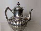 a silver tea pot sitting on a glass table
