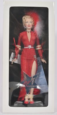 La poupée Barbie se trouve dans une boîte blanche ; elle porte une robe rouge et des chaussures rouges.