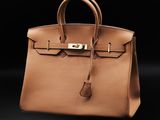 a brown leather handbag on a black background