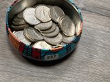 un bol rempli de pièces de monnaie posé sur une table en bois