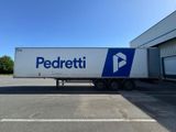 Le camion est garé devant un immeuble orné d'un logo bleu et blanc.
