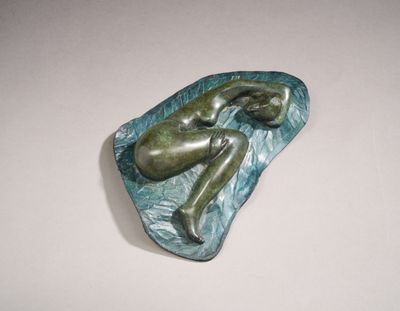 sculpture of a woman laying on a rock in the water