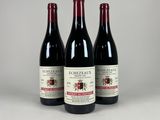 trois bouteilles de vin rouge posées côte à côte sur une table