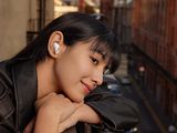 smiling woman leaning on railing with ear buds in her ears