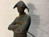 bronze statue of a man with a sword and hat on a white background