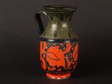 a green and red vase sitting on a black surface
