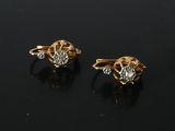 a pair of gold and diamond earrings on a black surface