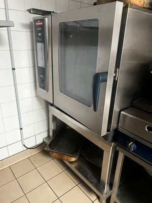 un four argenté posé dans une cuisine, à côté d'une cuisinière