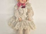 an old doll with blonde hair and a white dress sitting on a white surface