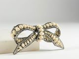 an image of a white bow brooch with pearls on it