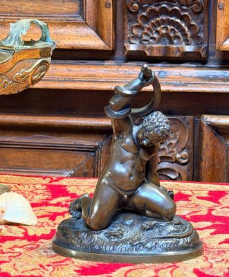 une statue en bronze représentant un garçon tenant un oiseau, posée sur une table