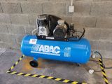 an air compressor sitting on top of a blue tank in front of a brick wall