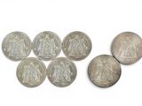 six coins of different sizes and shapes are shown on a white surface
