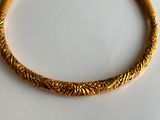 a close up of a gold bracelet on a white surface