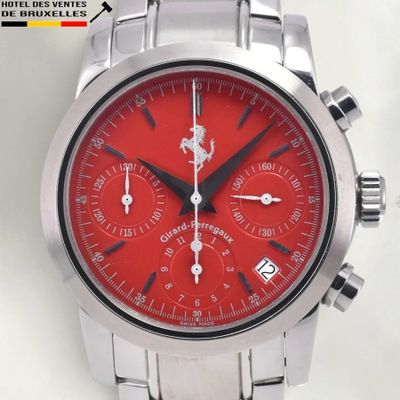 a close up of a wrist watch with a red dial