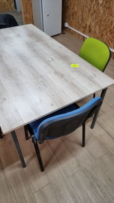 a wooden table with two chairs and a refrigerator in the background