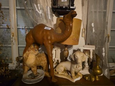 une statue de chameau posée sur une table, à côté d'une lampe