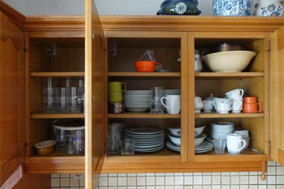 un placard sur lequel sont posés de la vaisselle et des tasses, dans la cuisine
