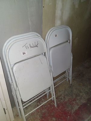 deux chaises pliantes blanches portant une inscription, dans un coin de la pièce