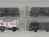 quatre wagons en noir et blanc dans des boîtes transparentes, posés sur une surface blanche