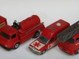 Plusieurs camions de pompiers miniatures sont alignés en rang sur une surface blanche