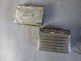 two silver cigarette cases sitting next to each other on a blue cloth