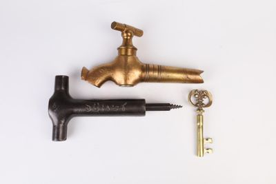 a brass faucet and a key on a white surface