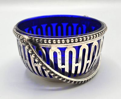 a blue glass bowl with a silver handle on a white surface