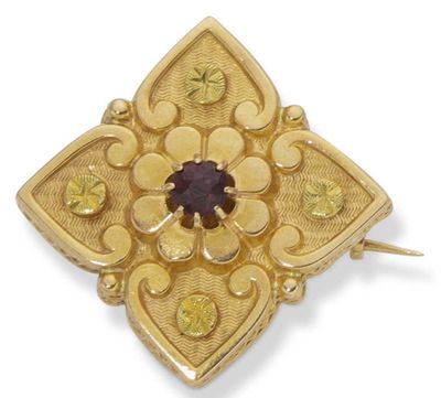 a close up of a gold broochle with a purple stone