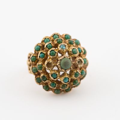 une image représentant une bague en or sertie de pierres vertes sur fond blanc