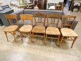 six wooden chairs in a room with a couch in the background