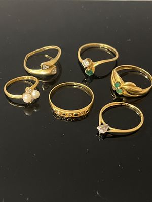 six bagues en or ornées d'émeraudes et de perles sur un fond noir