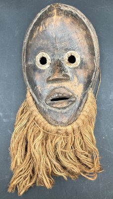 a close up of a mask with long hair on a black surface