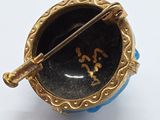 a blue and gold brooch with a pin in it