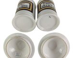 three empty beer bottles and two empty cups sitting next to each other